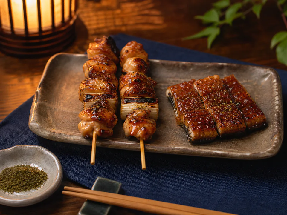 夏夜の食卓に並ぶタレ焼きの焼き鳥とうなぎの蒲焼き