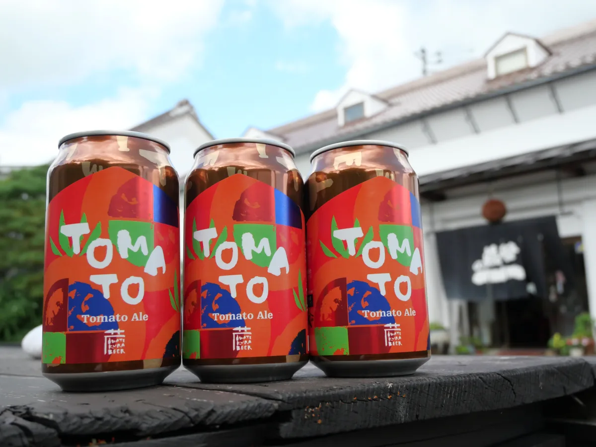 世嬉の一酒造の蔵を背景に並ぶ、一関産完熟トマトを使ったトマトビールの缶