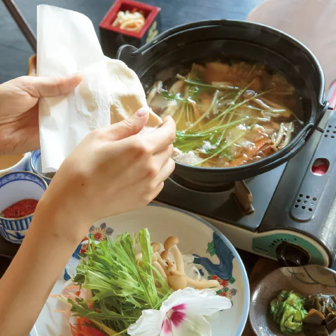 手切りはっとの生地を手で伸ばし、野菜の入った鍋へ加える様子